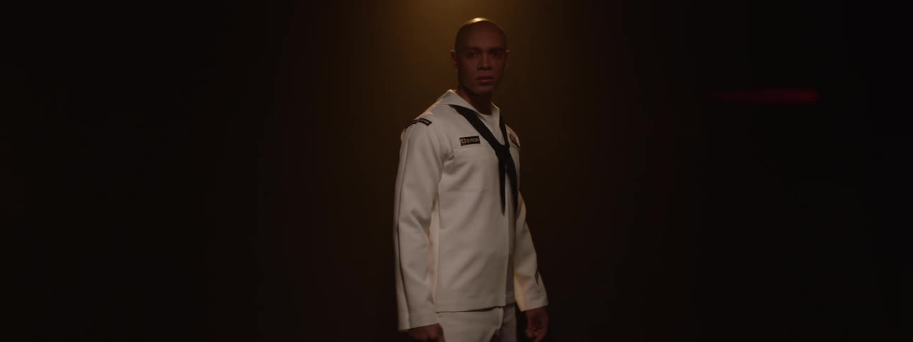 A navy officer standing in a spotlight