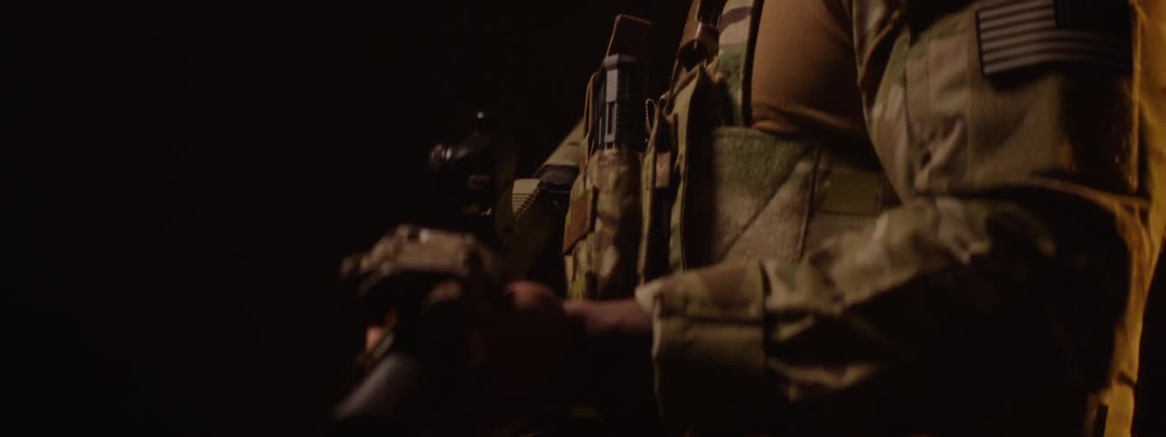 The video features a closeup of a person holding a black cylindrical object that appears to be a microphone in a dimly lit setting the lighting creates a strong contrast highlighting only parts of the persons arm and the microphone against a dark bac