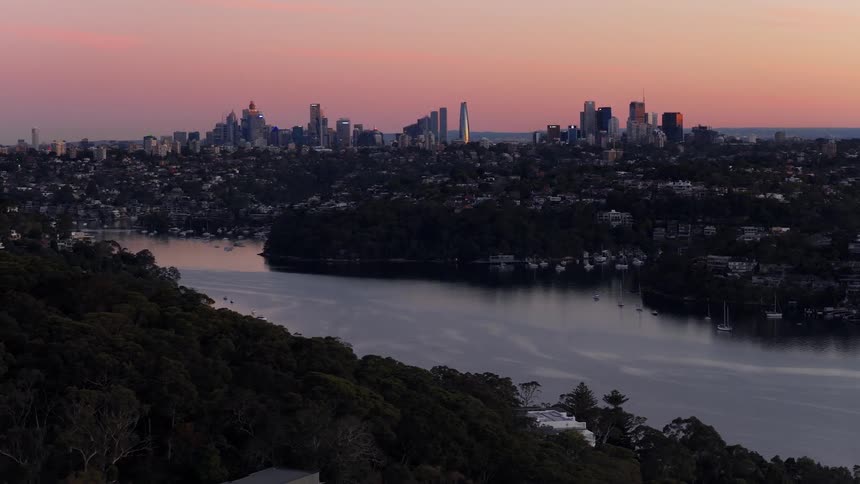 Sea canal surrounded by urban cities and skyscrapers on the horizon against a pink sky