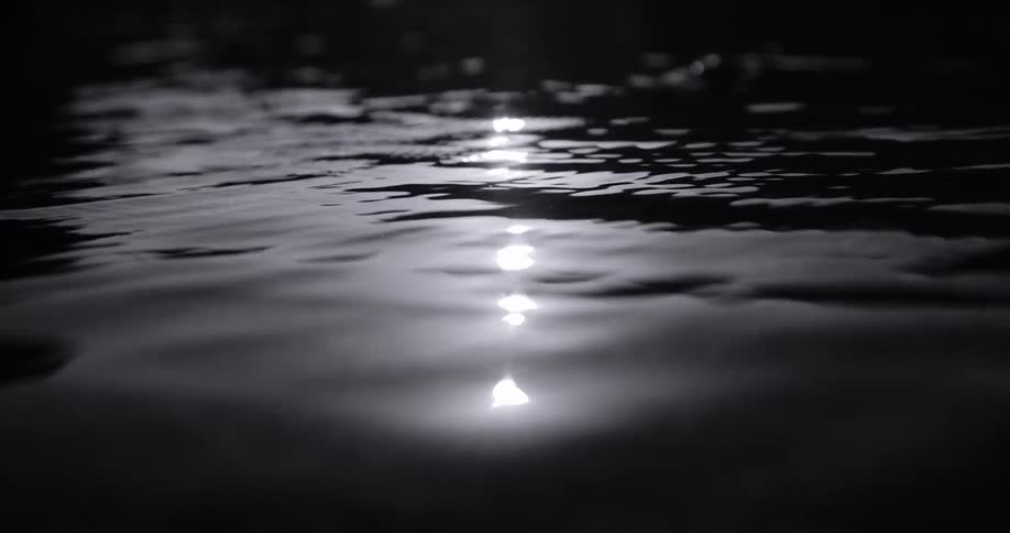 The video displays the surface of water with ripples and reflections of light creating a shimmering effect the scene is dark suggesting night or a lowlight environment with bright spots of light scattered across the water