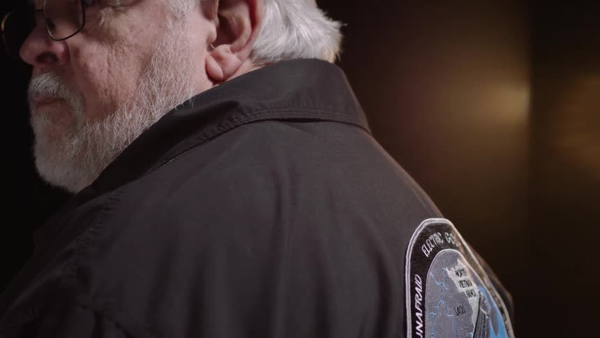 Closeup profile shot of an elderly man with prominent white hair and a white beard