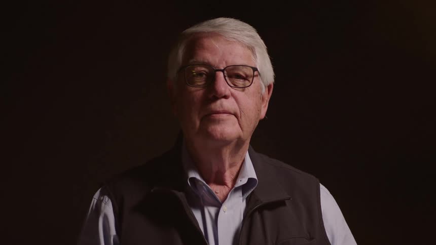 Elderly man with glasses in a lowlight space
