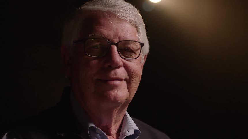 Elderly man with white hair and glasses with a happy expression