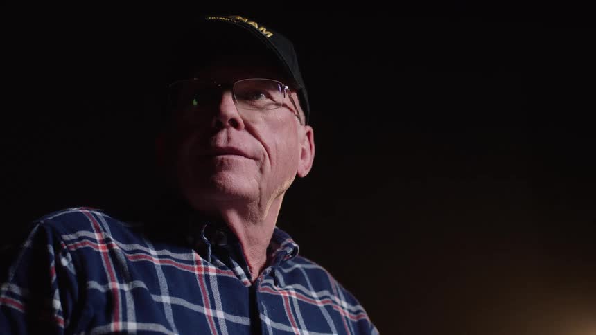 Elderly man with glasses and a cap looking to the side