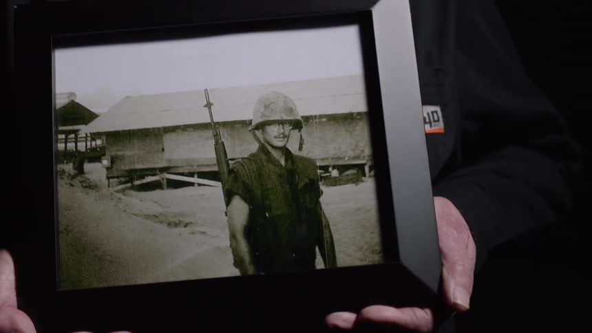 Pair of hands holding black and white photo of a military soldier with a rifle