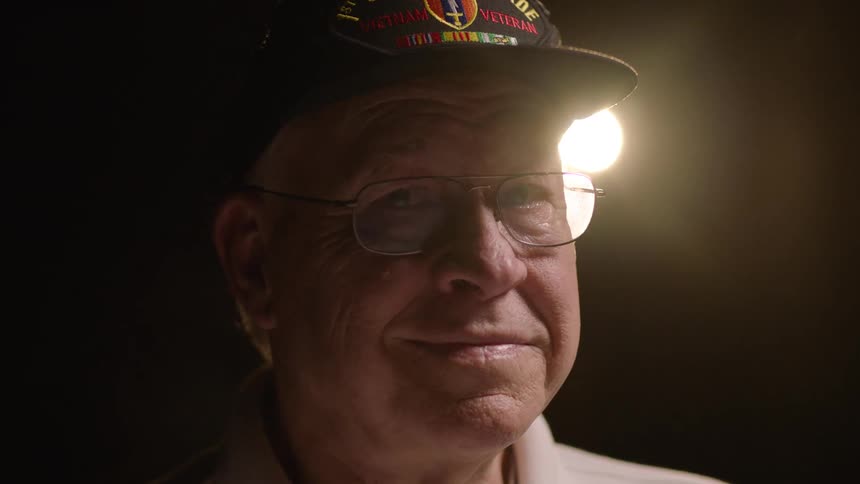 Close up portrait of a happy man wearing a face cap under yellow lighting