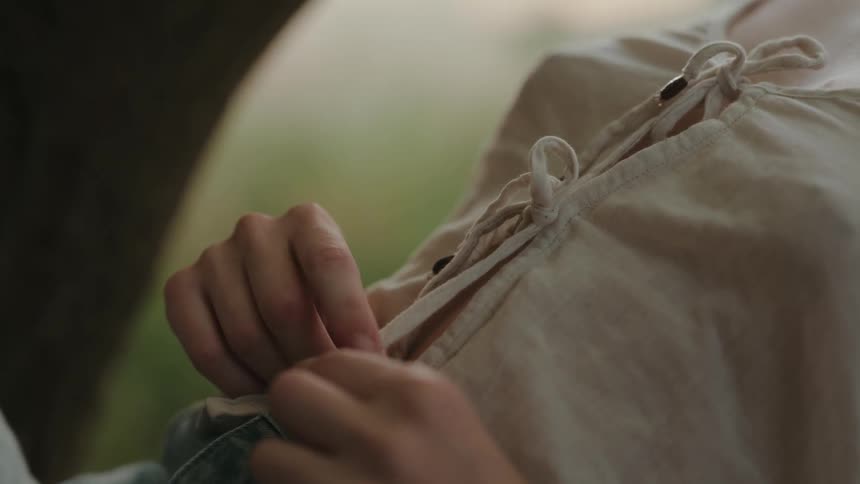 Woman leans back while she plays with the ties of her blouse