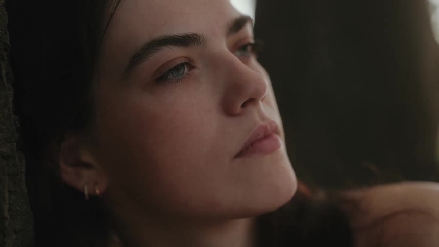 A young woman indoors deep in thought with her eyes closed