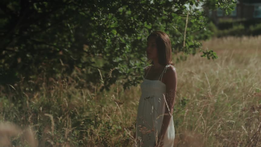 Woman in white dress walking through a field