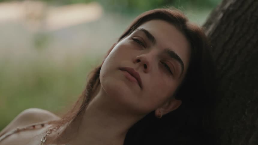 A girl is resting against the tree