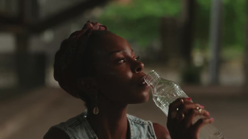 Woman outdoors drinking water from a glass bottle