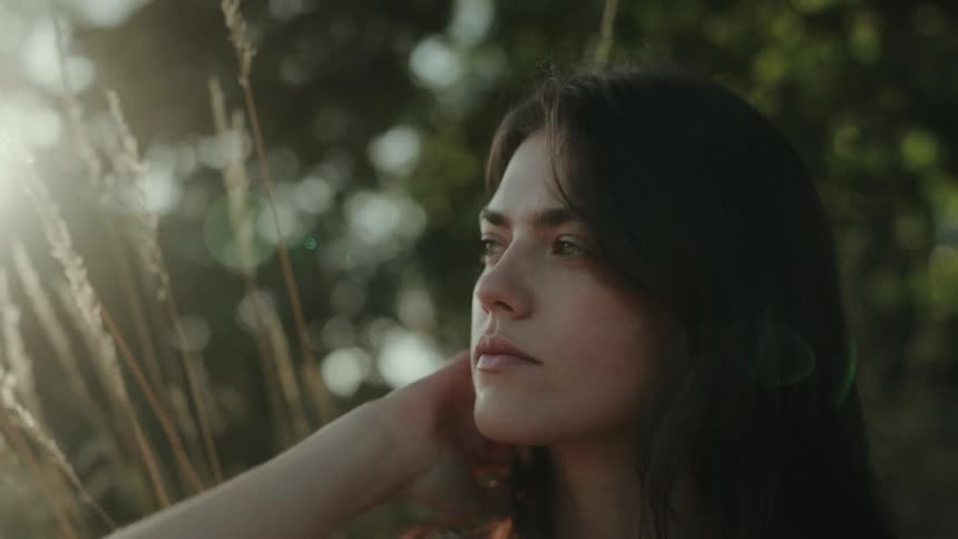 Black haired woman outdoors with trees in the background