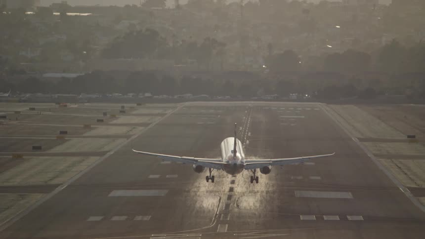 An airplane lands on a runway at sunset