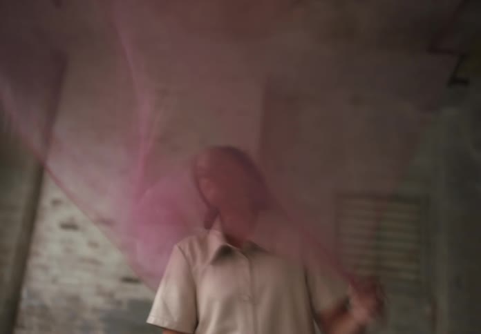 Blurry motion shot of a woman playfully tossing a sheer fabric indoors