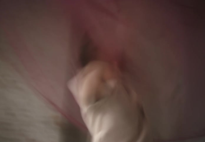 A young woman indoors playing by herself with a pink scarf
