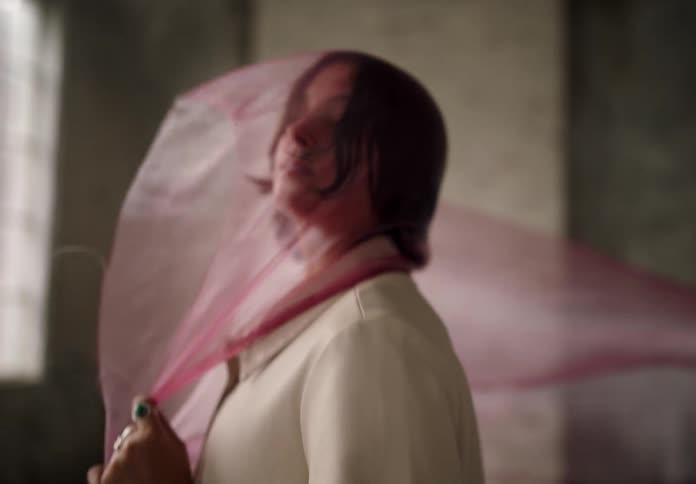 Woman twirls with pink fabric over face