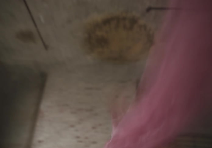 Woman dancing with a translucent pink scarf in an indoor space