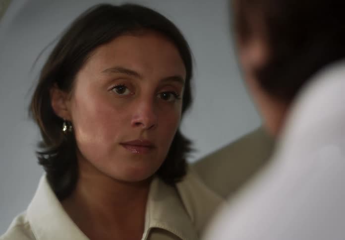 A woman looks at herself in the mirror with a calm expression
