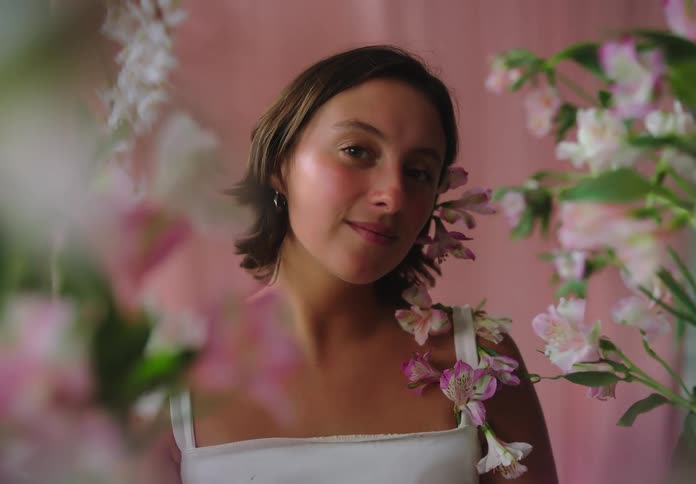 Woman with short hair with orchid flowers on the side of her face and shoulder