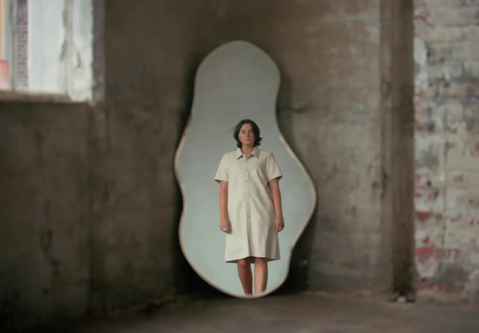 A woman stands in front of a mirror
