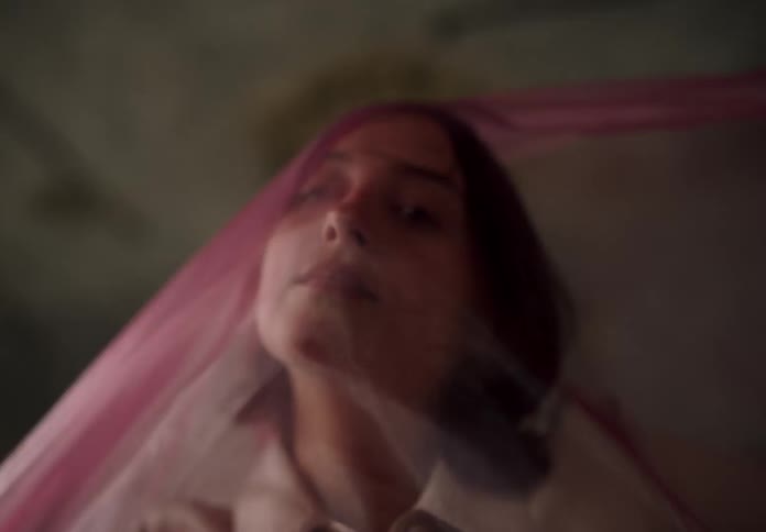 Woman with a translucent pink scarf passing over her face