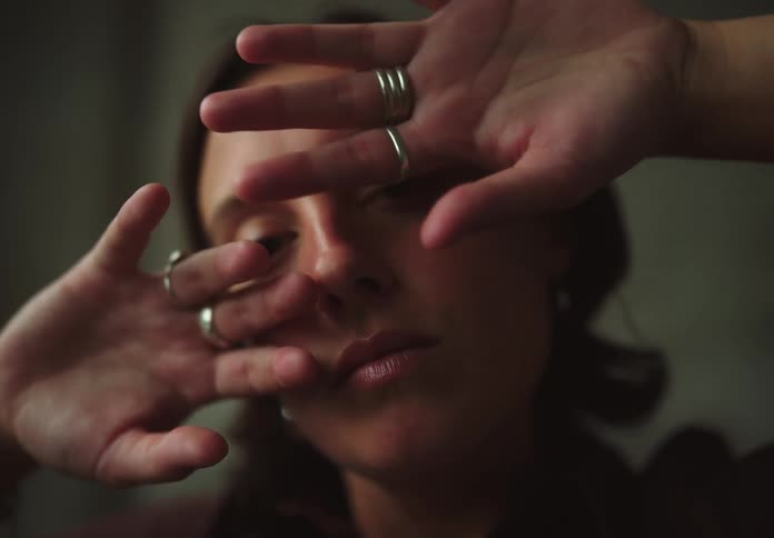 Woman with both hands with rings on her face