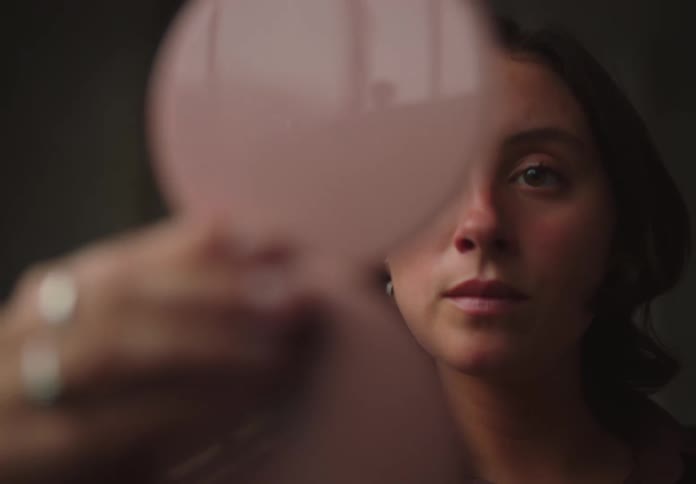 Woman looking at herself in front of a small mirror device