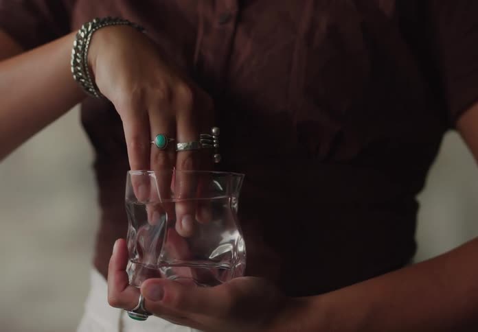 Womans hand inside a glass cup of water