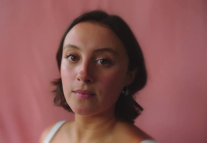 Portrait of a young woman with short hair and a pink cloth in the background in motion