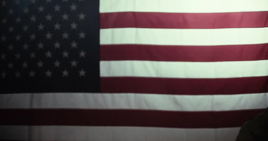 Woman slams down a folding chair repeatedly in front of an american flag
