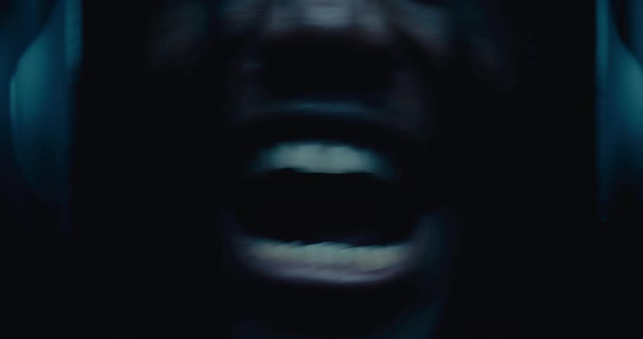 A closeup of a wide open mouth shows a black person laughing or shouting with intensity