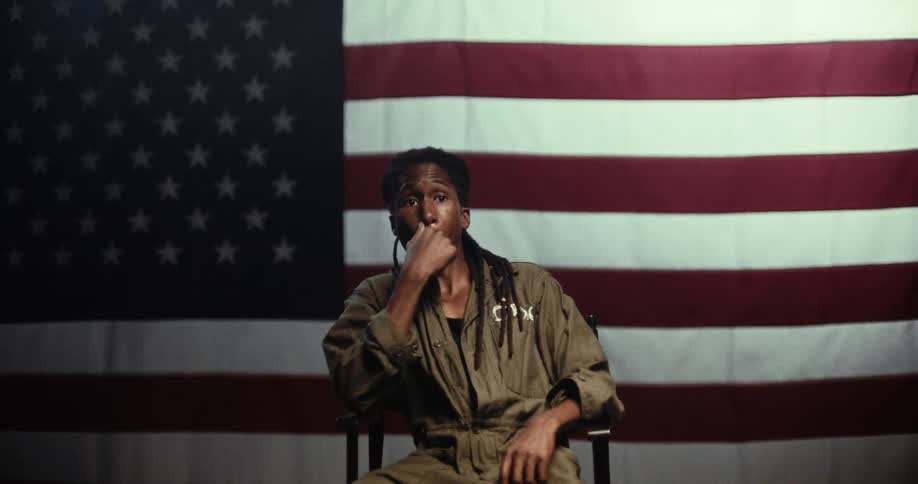 The man walks and sits in front of the american flag