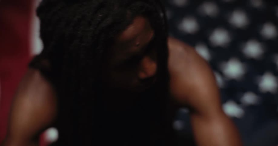 A closeup of a black person with long braids looking sad is sitting near a backdrop of stars