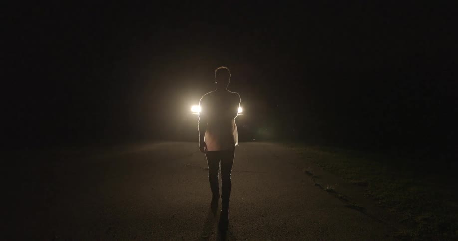 Man walks away from a vehicle at night