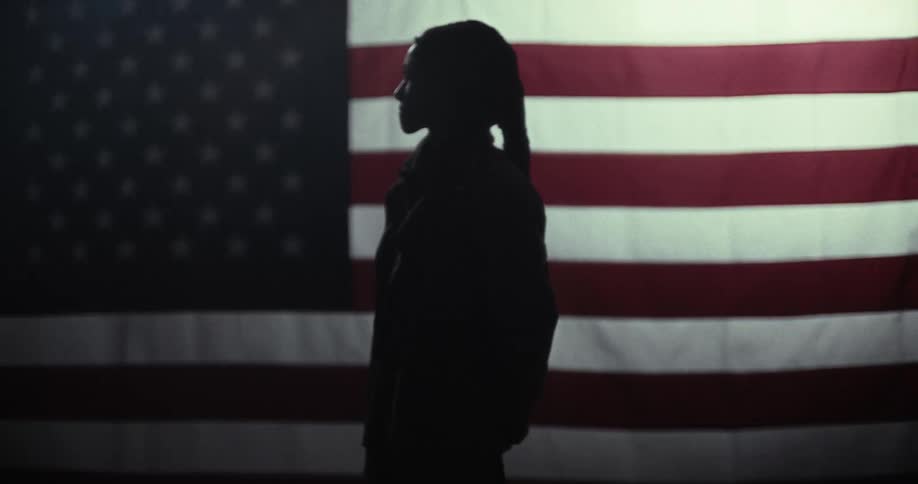 Silhouette of a man with long hair and the united states flag in the background
