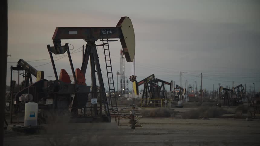 Oil pump pumping on a industrial landscape under a muted sky at dusk