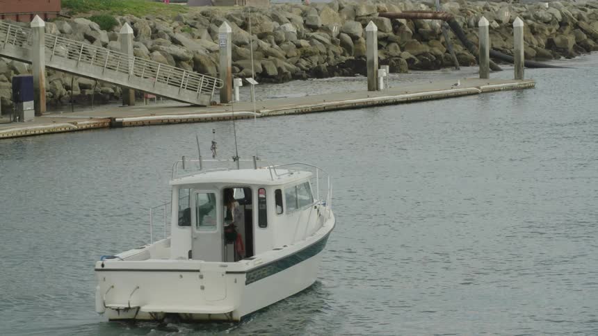 Small white motorboat cruising slowly through the calm waters of a harbor