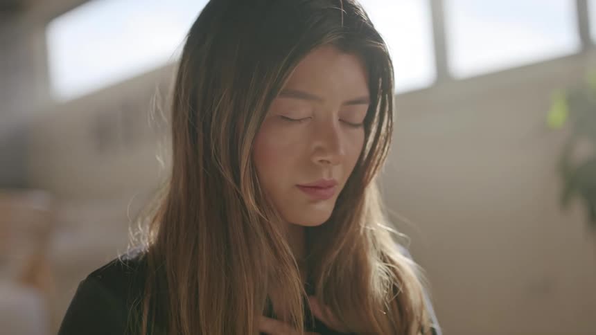 The woman is meditating with her head lowered