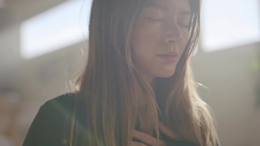A woman meditates with her hand on her chest