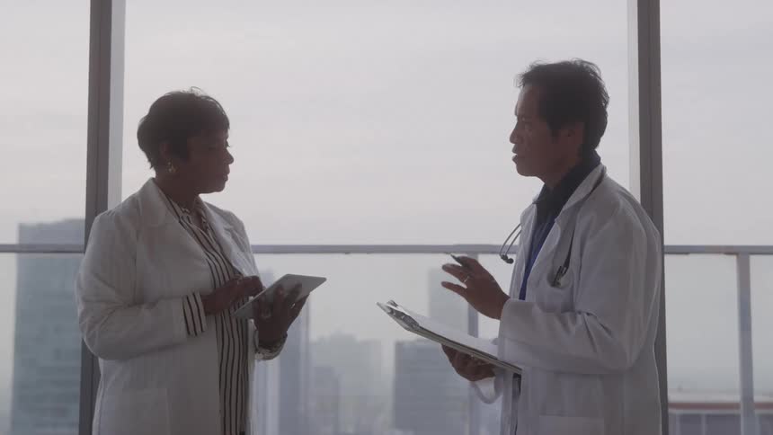Two doctors have a discussion by the window