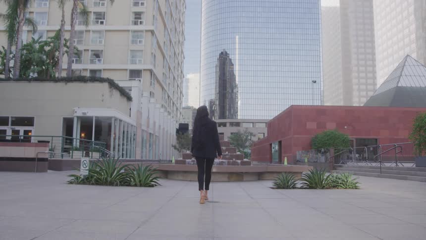 Woman in blazer and formal wear walking in a square in the metropolis