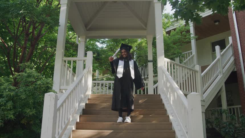 Smiling woman in graduation gown showing diploma