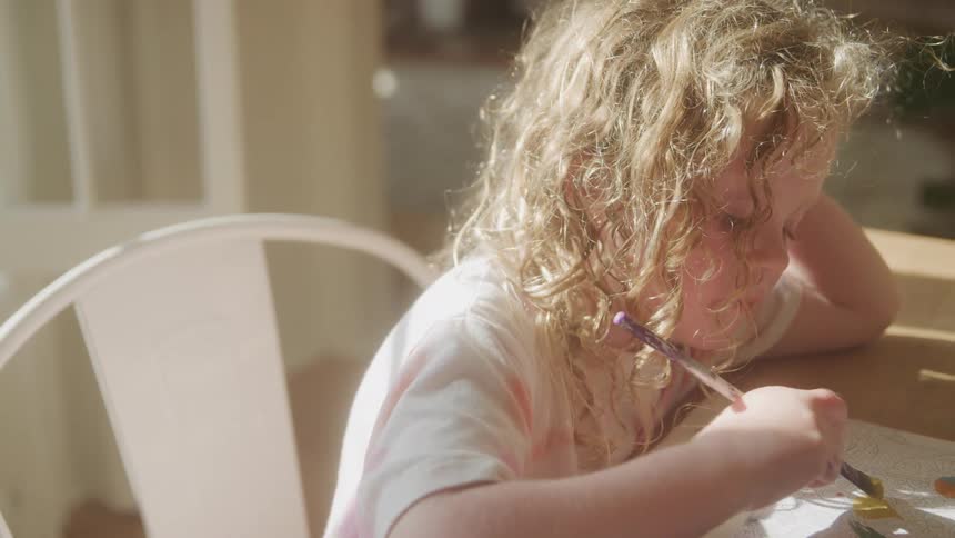 The girl is painting on a piece of paper