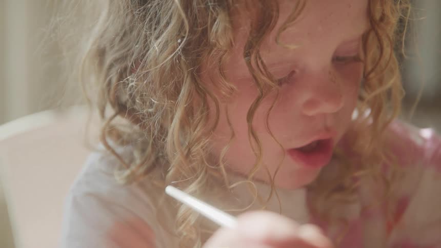 Toddler girl holds a paintbrush while she concentrates