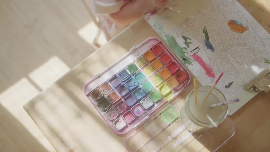 Child with a paintbrush painting on the table