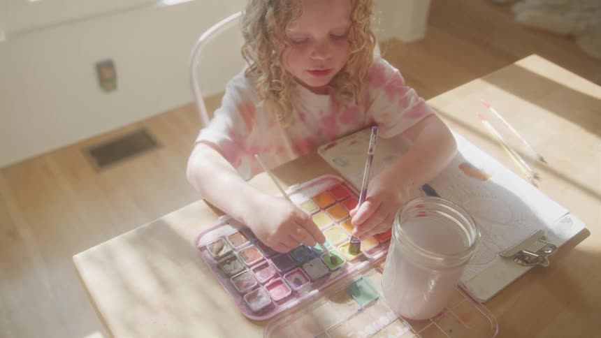 The little girl is mixing water color paints