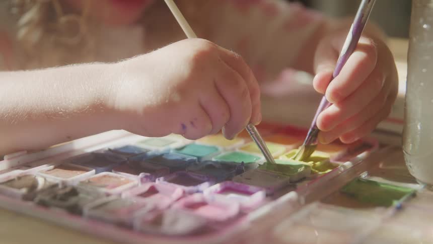 Pair of childs hands with brushes playing with paint