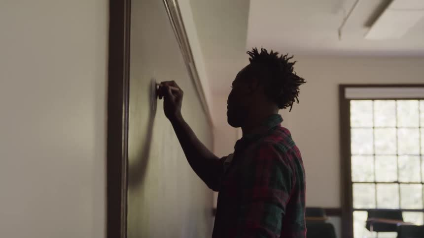 The student is writing on the chalkboard