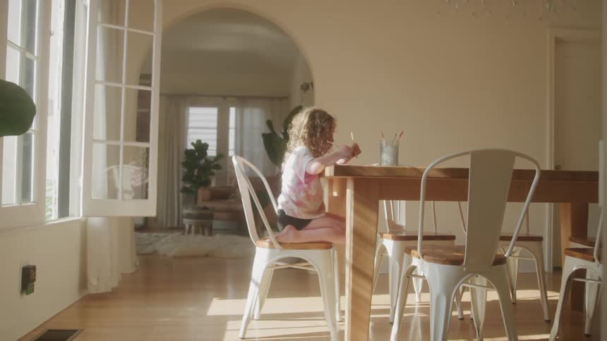Little blonde girl sitting at a table drawing