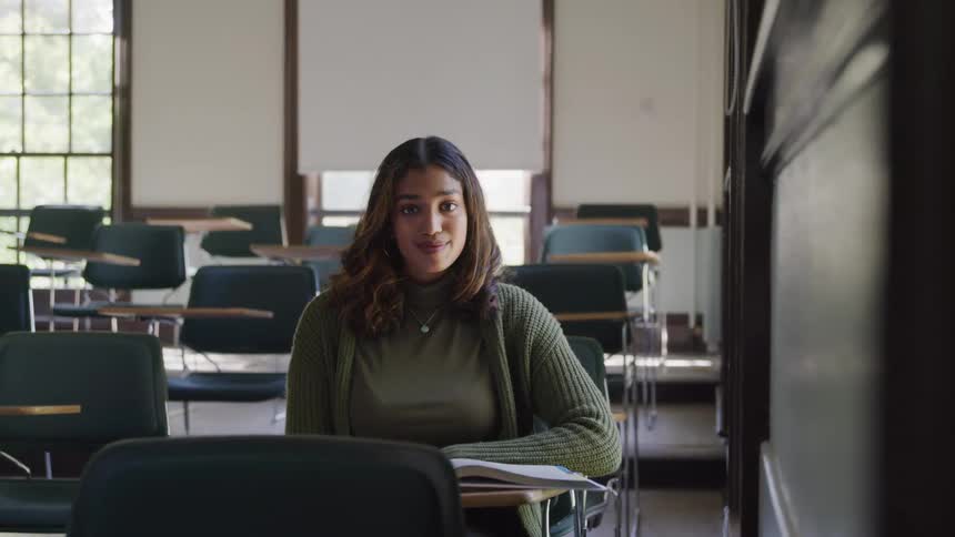 Woman with happy expression sitting in an empty classroom